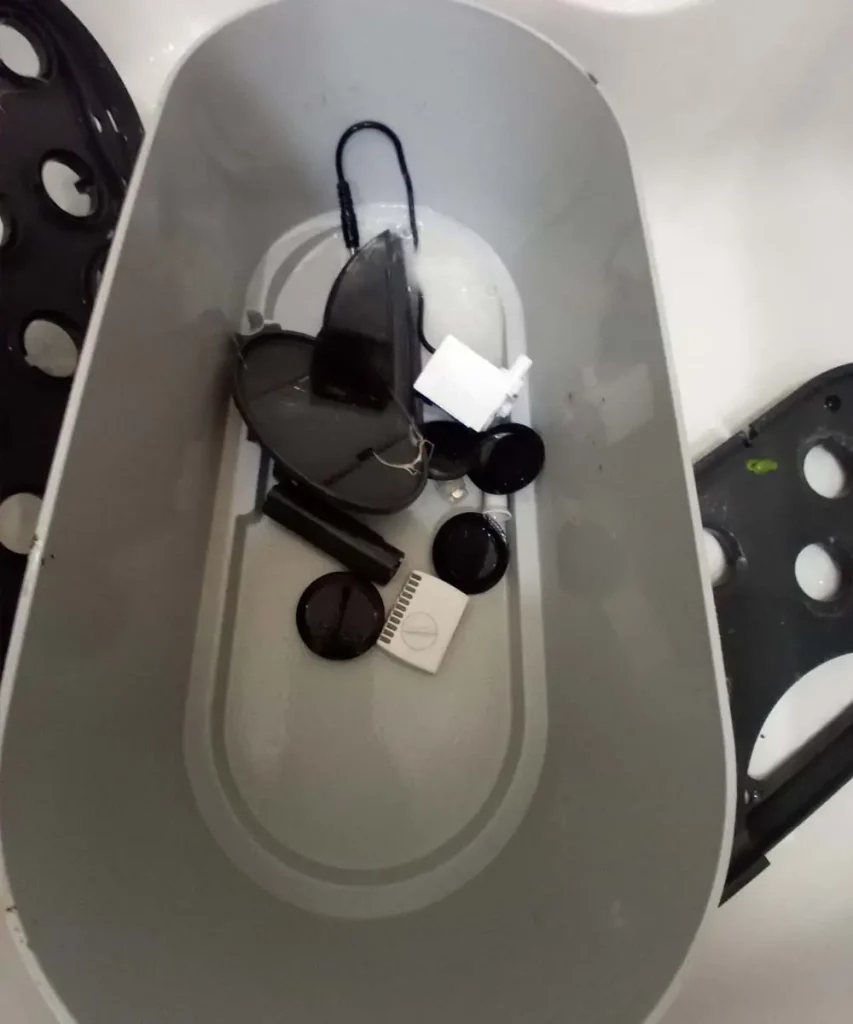 An AeroGarden Bounty reservoir bowl completely disassembled for cleaning, with internal water pump components and plastic covers laid out inside the basin.