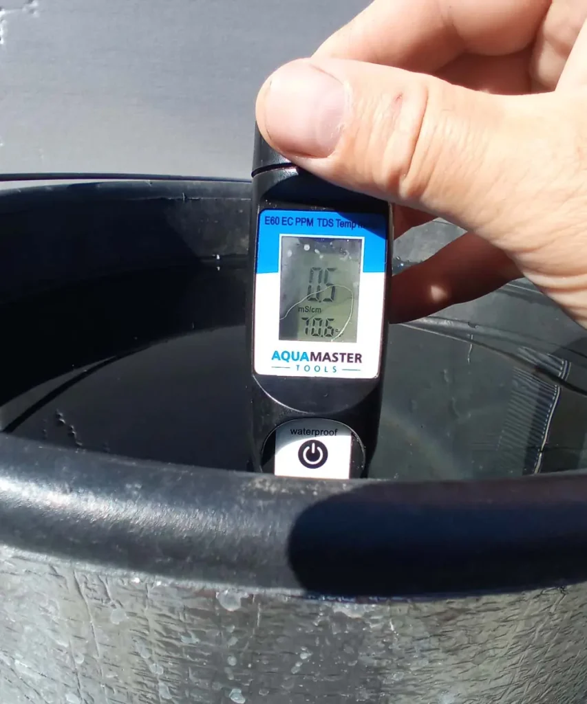 EC meter showing 0.5 mS/cm and a reservoir water temperature of 70.6°F (21.4°C) inside an insulated hydroponic reservoir.