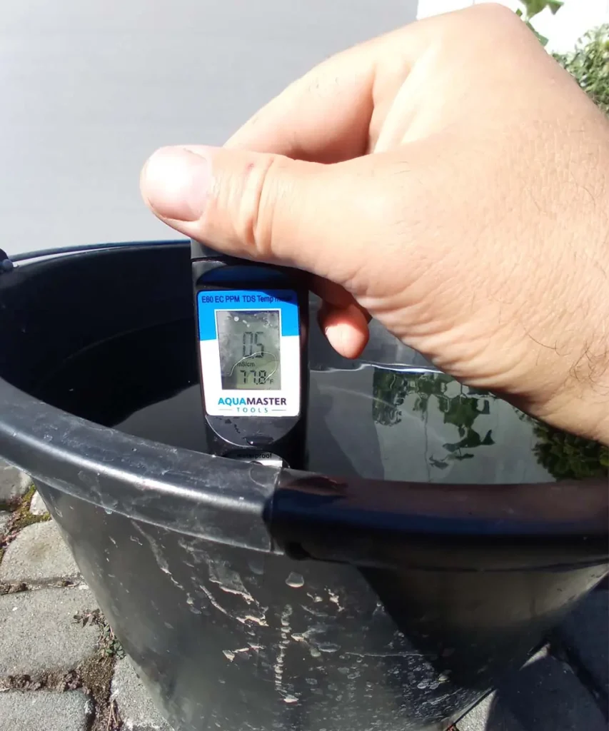 Hydroponic nutrient solution measured at 77.8°F (25.4°C) using a digital EC meter in a black reservoir.